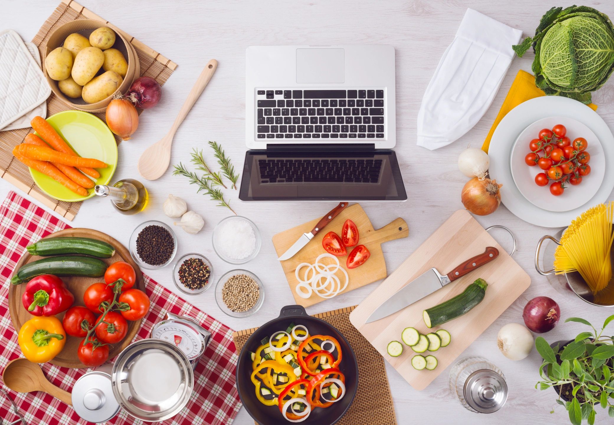 Home kitchen table top view with laptop, food.
